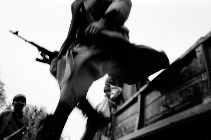 AFGHANISTAN. Kalakata front line, Northeast region. A Northern Alliance soldier jumps out from the truck bringing him to the front line. 2001.