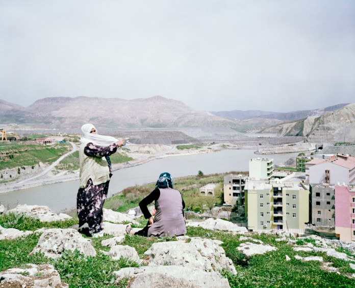 Women are standing on top of the dam construction site and city of New Ilisu where construction are being built and resort hotel for the hot springs. Turkey